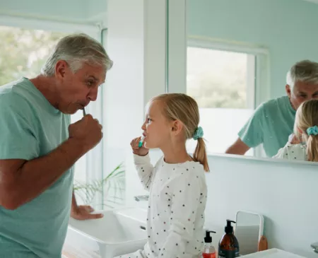 older man and granddaughter brushing teeth together
