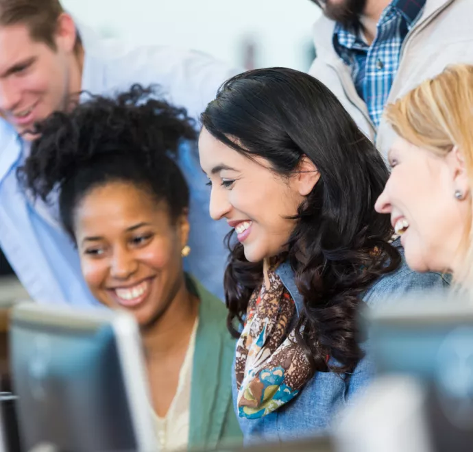 group of coworkers looking at computer happily