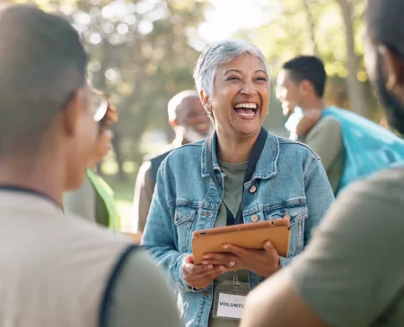 older woman laughing outside with tablet in hands