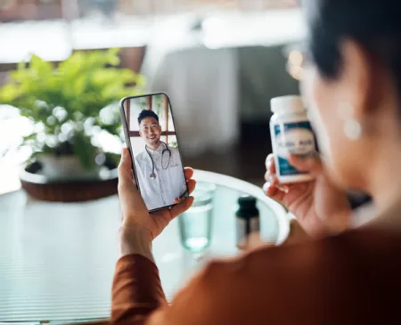 patient on phone with doctor and holding pill bottle